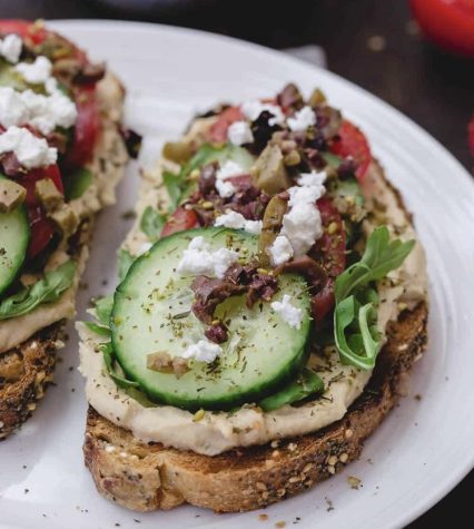 Mediterranean-style breakfast toast is a nourishing meal that utilizes hummus, feta cheese, and an assortment of vegetables. This aesthetic picture is on The Mediterranean Dish, a food blog that features a variety of other Mediterranean cuisine. Go to the link for this hummus toast recipe!