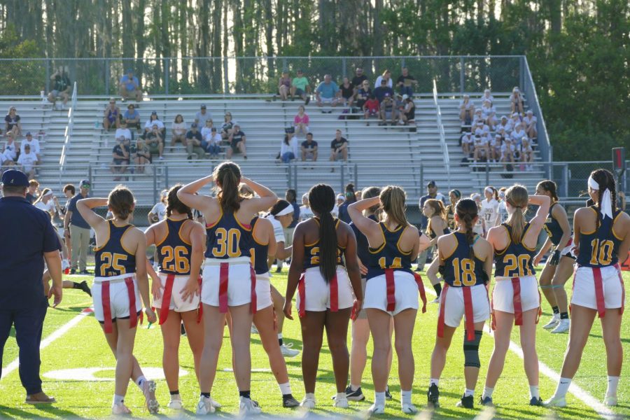 The flag football Lady Warriors stand on the sidelines, watching their teammates take on the Alonso Ravens. Watching the plays early on left them anticipating the rest of the game. Photo Courtesy of Alyssa Galang.  