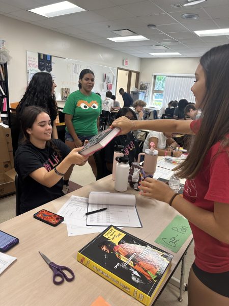 Junior Kelsey Brink, handing out the new 2023-2024 yearbook. The staff has worked tirelessly and has put in
hundreds of hours to complete this
work of art. Photo courtesy of Autumn Brown