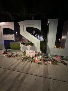  A memorial on FSU’s campus where students are leaving flower bouquets and signs to honor those lost and advocate for change. Following the tragic event, an official vigil was held to honor the lost lives and students have come together recently to show their support. Photo courtesy of Autumn Brown.  