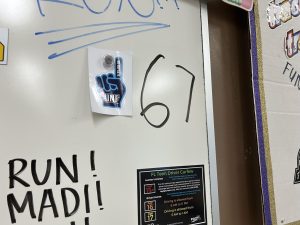 The photo above is of the 6 7 meme written on Coach Baldwin’s Driver’s Ed classroom whiteboard by an unknown student. The 6-7 meme has been gaining popularity among teenagers.  Photo courtesy of Seth Demetroulis