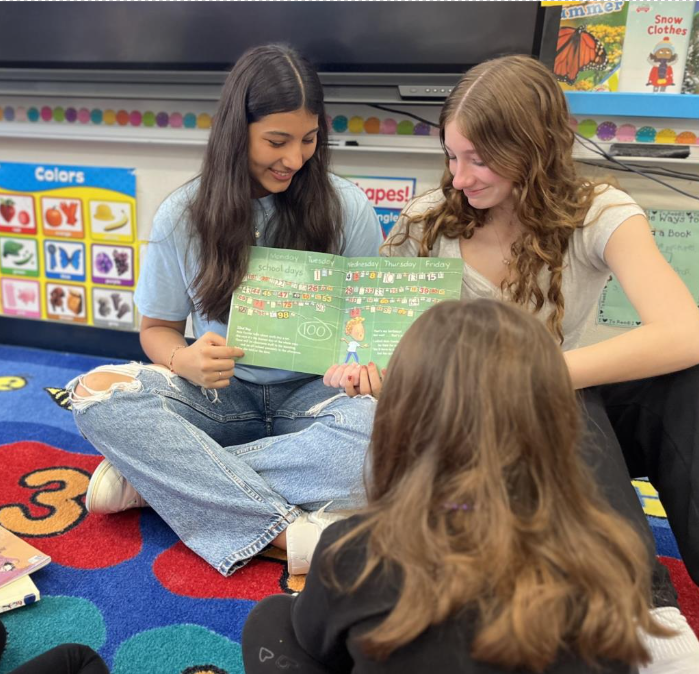 Left to Right: Marcela Canaveral (9) and Kalista Sivils (9) reading to kindergarten students at McKitrick Elementary School. This photo was taken at the last club meeting in January.