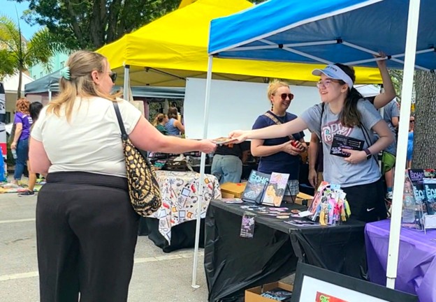 Echo Lit Mag Co-Editor in Chief, Keirsten Lee, handing out flyers to people walking through the festival. The flyers were designed by a member of The Echo’s alumni. Photo Courtesy of Weather Riley.